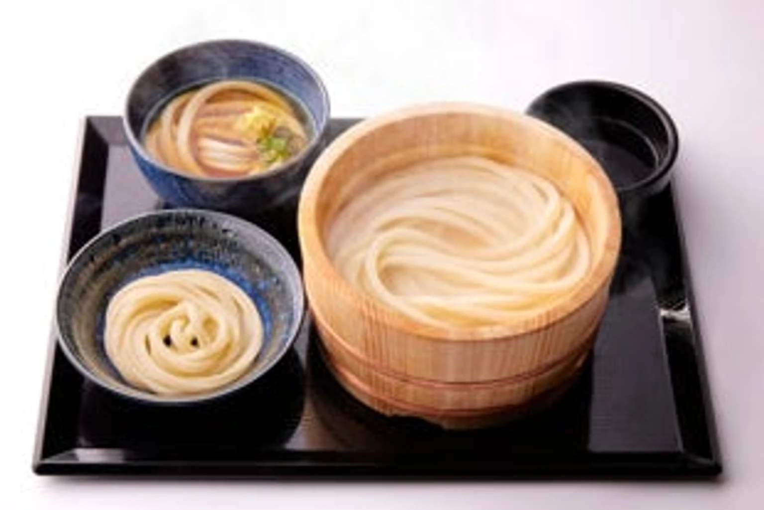 桶の釜揚げうどんと、かけうどん・醤油うどんを並べた三種の利きうどんの提供写真