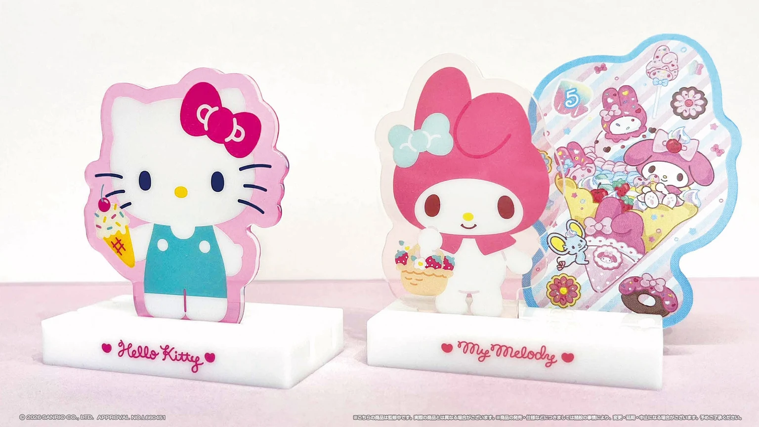 ハローキティとマイメロディのアクリル製カードスタンドが、キャラクターの形をしたトランプを支える商品写真。