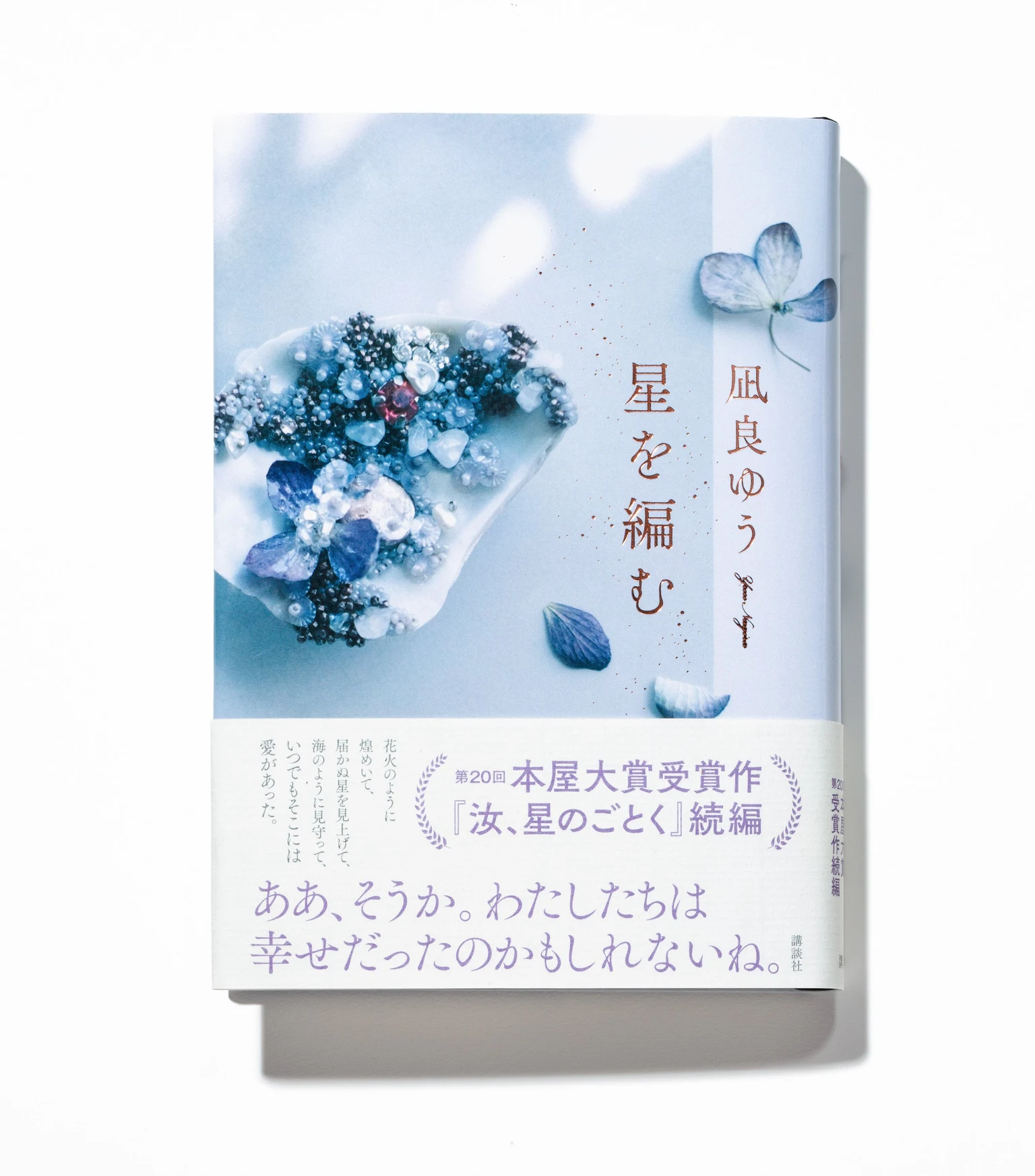 凪良ゆう『星を編む』の書籍を撮影した公式写真。淡い青と白の表紙に紐の意匠がある。