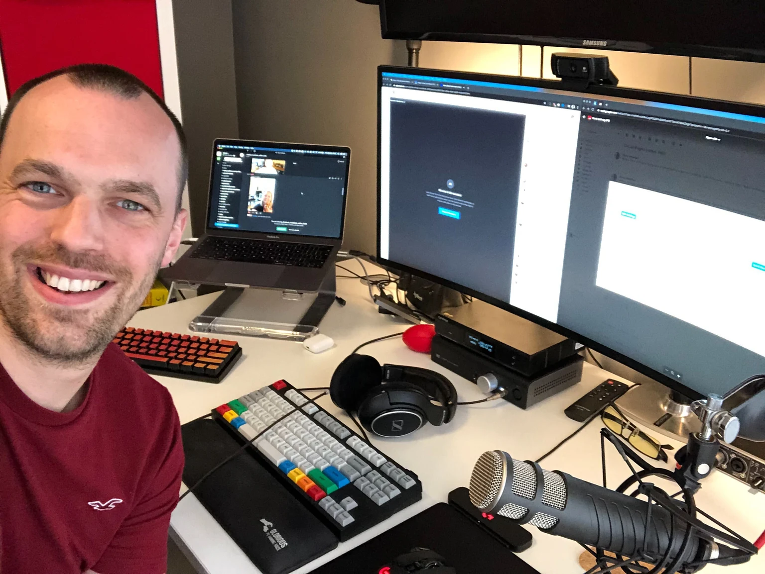 GitLabのチームメンバーSimon Mansfield氏が、複数の画面とキーボードを備えた作業机の前にいる