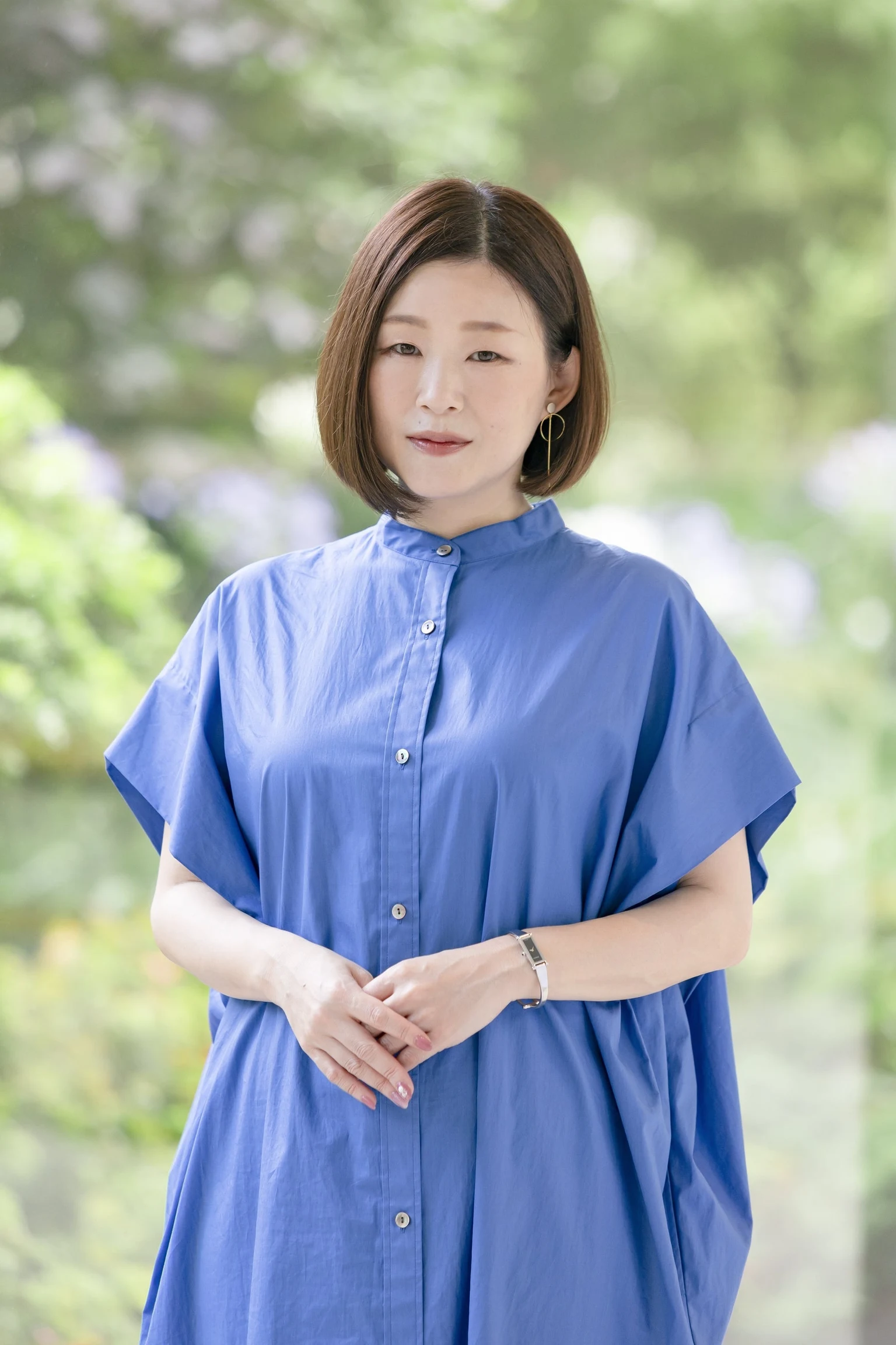 青い服を着た小説家・凪良ゆう。