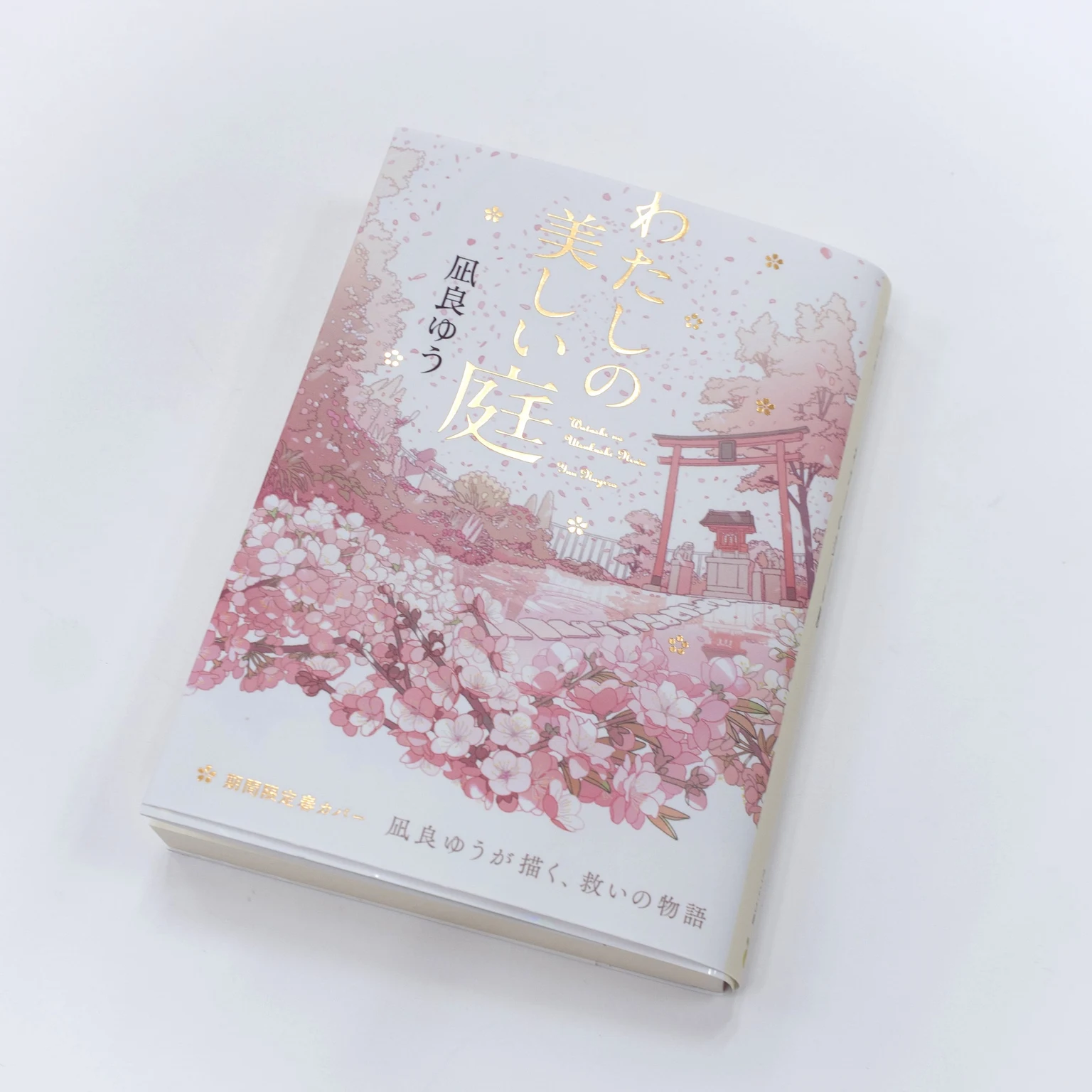 春の花々と鳥居を描いた期間限定カバーをまとった『わたしの美しい庭』の書籍写真。