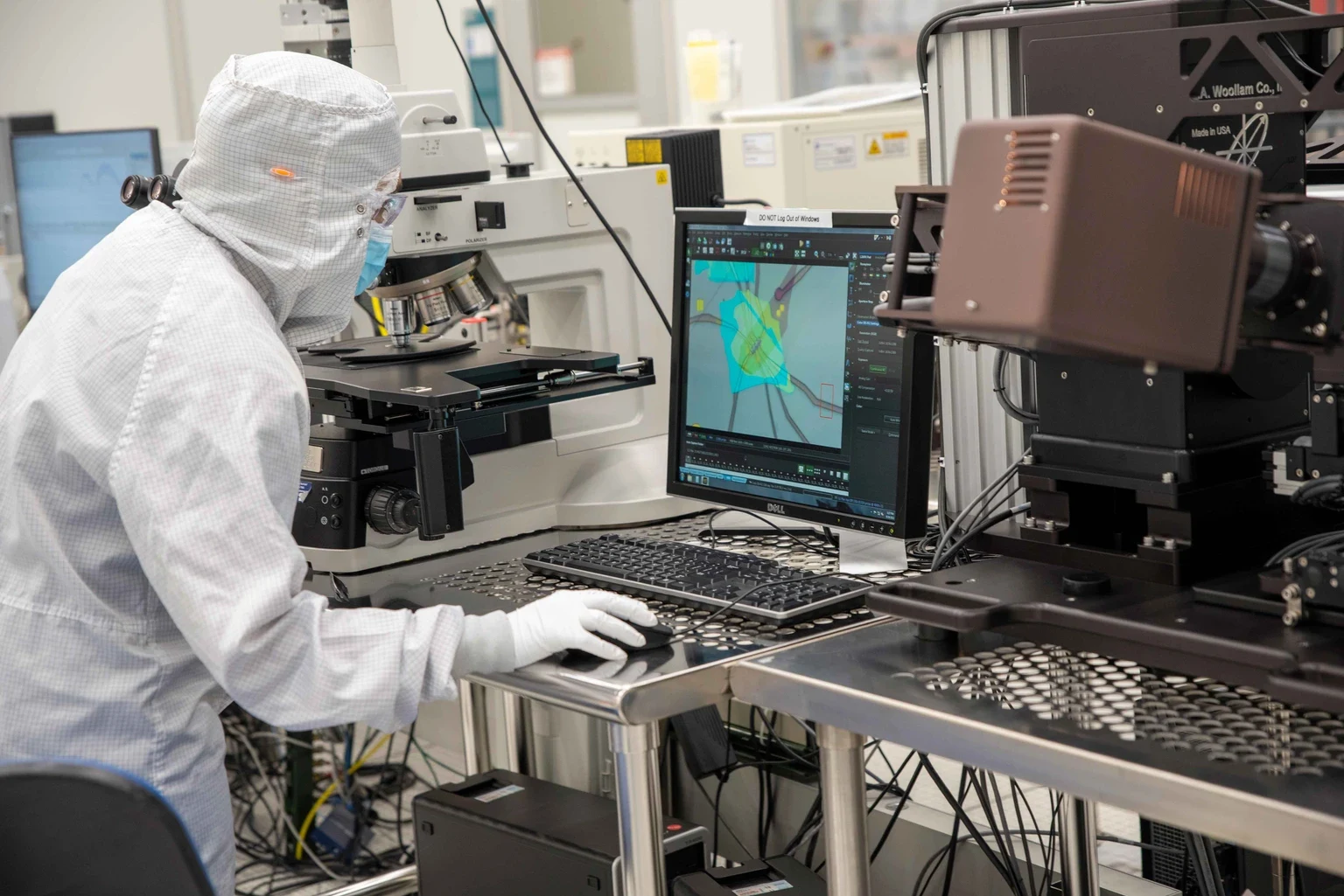 クリーンルームで顕微鏡とコンピューター画面を使い、試料を確認するNIST NanoFab利用者